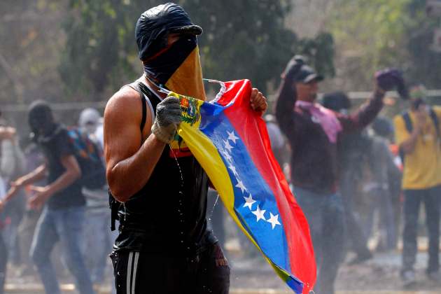 An anti-government protester is soaked by a water cannon during clashes with the police in Caracas