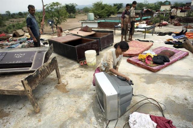 Varias personas personas tratan de salvar algunas de sus pertenencias tras las inundaciones en la localidad de Kangrail, a 28 kilómetros de Jammu, la capital invernal de la Cachemira india. EFE/Jaipal Singh