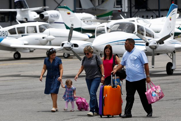 Passengers walk at the airstrip as they arrive at Charallave airport outside Caracas