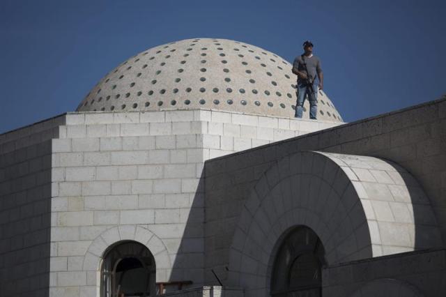 Un policía vigila en el tejado de la sinagoga tras el ataque contra una sinagoga en Jerusalén (Israel) hoy, martes 18 de noviembre de 2014. Al menos seis personas, entre ellas los dos presuntos atacantes, murieron hoy en un tiroteo en una sinagoga y yeshiva (seminario rabínico) del barrio ortodoxo de Har Nof, en Jerusalén Oeste, informó la Policía local. EFE/Abir Sultan