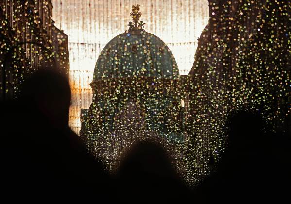 Visitors walk past Christmas lights towards Hofburg Palace's Michaeler Cupola in Vienna