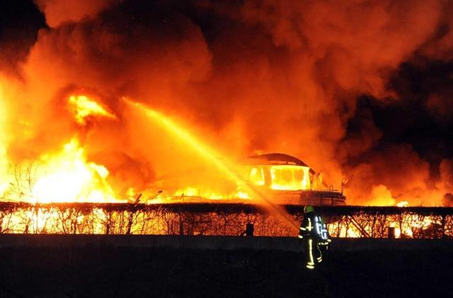 Los bomberos intentan apagar las llamas tras el incendio declarado en un puerto para yates en Roermond, en el sur de Holanda, anoche. El centro de Roermon fue cerrado al tráfico en la mañana de hoy, miércoles 17 de diciembre de 2014, tras el incendio que ha causado la propagación de amianto sobre la localidad. EFE/Ginopress