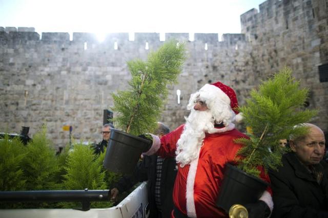 Un hombre vestido de Papá Noel vende árboles de Navidad en la puerta de Jaffa en la muralla de Jerusalén (Israel) hoy, lunes 22 de diciembre de 2014. EFE/Abir Sultan