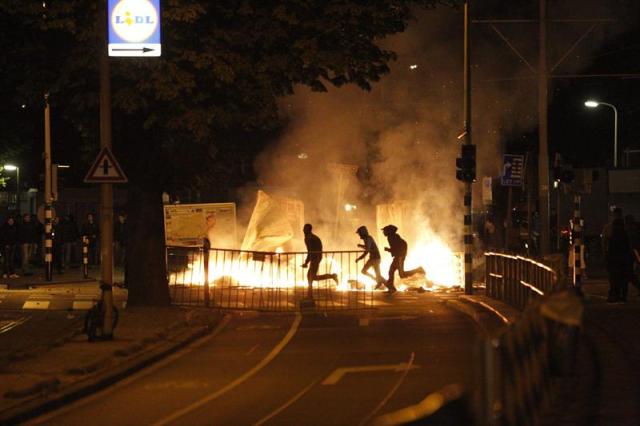 Varios manifestantes corren tras una barricada en llamas durante unos disturbios en el distrito Schilderswijk de La Haya (Holanda) anoche. Los manifestantes se concentraron para protestar por la muerte de Mitch Henriquez, un hombre de Aruba de 42 años que murió el 28 de junio en el hospital tras ser arrestado en un festival de música el día anterior. EFE/Arie Kievit