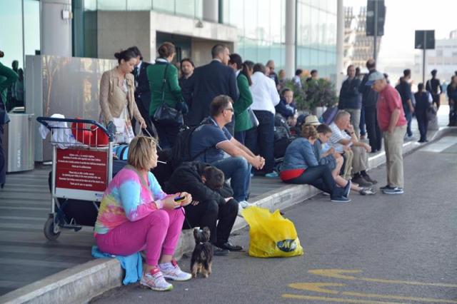 Varios pasajeros esperan la salida de sus vuelos en el aeropuerto Leonardo Da Vinci tras declararse un incendio, en Fiumicino, Roma (Italia) hoy, jueves 7 de mayo de 2015. El aeropuerto de Fiumicino comenzará gradualmente su actividad a partir de las 12.00 hora local (10.00 GMT), después de que un incendio que se declaró anoche y provocó graves daños materiales en la terminal T3 quedara extinguido. EFE/Telenews