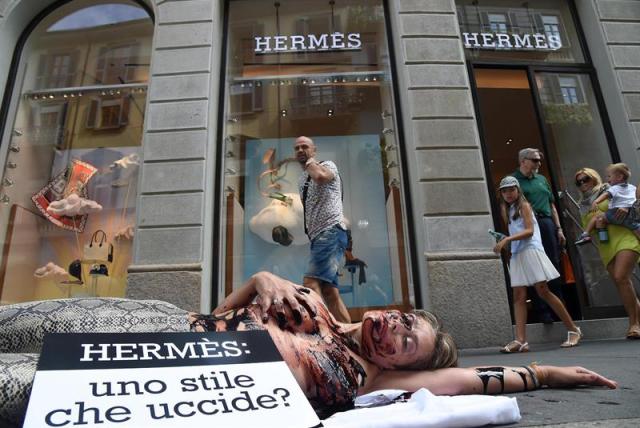 Una activista de la organización PETA junto al lema "Hermès: ¿un estilo que mata?" participa en una protesta delante de la tienda que la firma francesa Hermès tiene en Milán (Italia) hoy, 30 de julio de 2015. La cantante británica Jane Birkin ha pedido a la firma que cambie el nombre al mítico bolso de cocodrilo que lleva su nombre después de conocer la crueldad de los métodos empleados en la matanza a través de un vídeo de la asociación de defensa de los animales PETA. EFE/Daniel Dal Zennaro