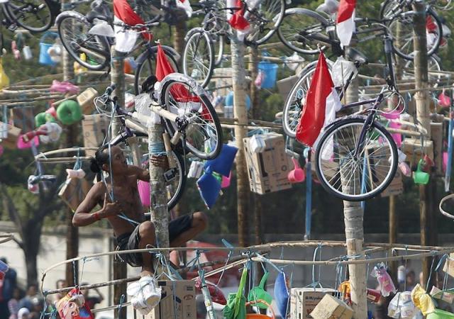 Un indonesio participa en un concurso de escalada de un poste para alcanzar los regalos dejados en lo alto durante las celebraciones por el 70º aniversario de la Independencia en el Palacio Presidencial Merkeda en Yakarta (Indonesia) hoy, 17 de agosto de 2015. EFE/Adi Weda