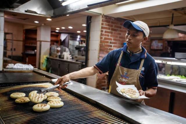 Daniel González prepara arepas en un restaurante de Caracas. El analista Miguel Octavio utiliza los precios de esta popular comida nacional para seguir la inflación en el país. PHOTO: MIGUEL GUTIÉRREZ PARA THE WALL STREET JOURNAL