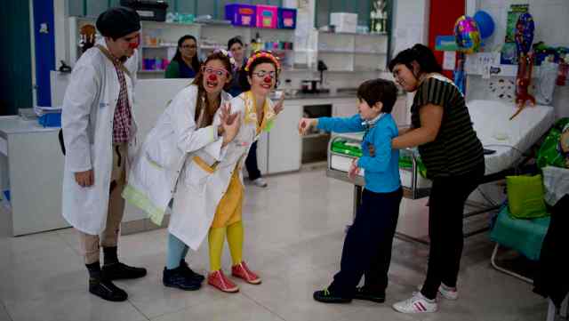 Los payasos Gonzalo Amor, a la izquierda, Romina Amato, en el centro, y Erika Véliz actuán para Alejo Lacone en un hospital pediátrico de la provincia de Buenos Aires, Argentina, el jueves 4 de junio de 2015. El  niño recibe terapia del humor, que por ley es obligatoria en todos los hospitales de la provincia. (AP Foto/Natacha Pisarenko)