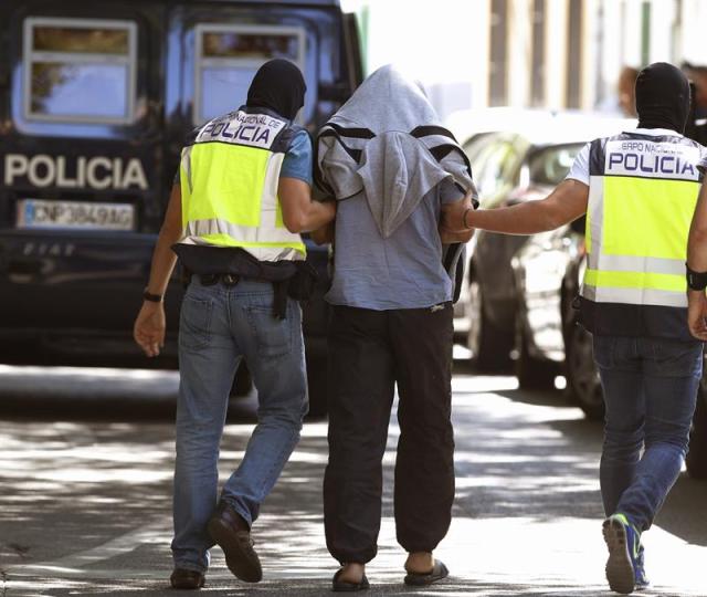 El supuesto yihadista detenido en la localidad madrileña de San Martín de la Vega, dentro de una operación en la que agentes de la Policía Nacional española y de la DGST de Marruecos han detenido la localidad madrileña y en varias ciudades marroquíes a catorce personas supuestos miembros de una red que captaba y enviaba combatientes para el Estado Islámico o Daesh, acompañado de dos policías par ael registro llevado a cabo en el locutorio que gestiona. EFE/Sergio Barrenechea