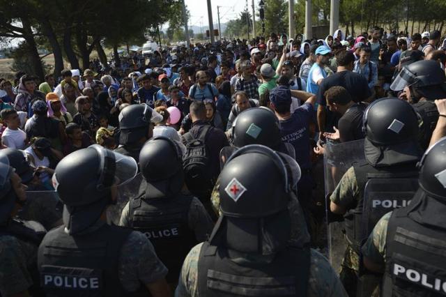 Inmigrantes controlados por la policía macedonia cruzan la frontera entre Macedonia y Grecia, cerca de Gevgelija (Macedonia) hoy 26 de agosto de 2015. Macedonia sigue permitiendo la entrada de refugiados a través de su frontera con Grecia y, aunque la situación es de calma, persiste la preocupación por la llegada diaria de miles de personas. Según datos ofrecidos por el ministro del Interior macedonio, Mitko Cavkov, solo el pasado sábado llegaron a Gevgelija, la primera ciudad tras la frontera, 8.000 refugiados, lo que equivale a un tercio de la población de la ciudad. EFE/Vassil Donev