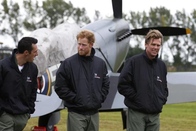 El príncipe Enrique (centro) conversa con el director de la Academia Boultbee, Matt Jones (dcha), y su fundador, Nathan Foster (izdA), durante un acto conmemorativo por el 75 aniversario de la Batalla de Inglaterra celebrado en el aeródromo de Goodwood, cerca de Chichester en el Oeste de Sussex (Reino Unido), hoy, 15 de septiembre de 2015. EFE/Luke Macgregor