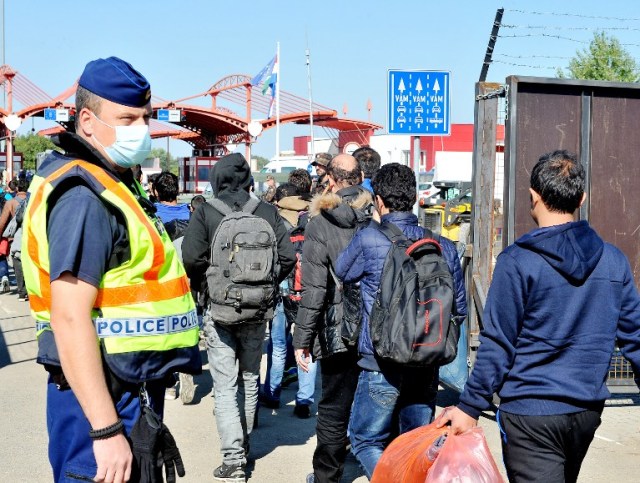 Migrants and refugees carry their belongings from bus as they prepare to cross the Croatian -Hungarian border in village of Baranjsko Petrovo Selo, near the North-Eastern Croatian town of Beli Manastir, on October 2, 2015. The Croatian sun has given way to rain and the temperature has dropped, but refugees and migrants continue to stream into the country, forcing officials and charities to scramble to prepare for wintry conditions. More than 90,000 migrants, many of them fleeing conflict in the Middle East, have transited through Croatia since mid-September after EU member Hungary closed its border with Serbia, forcing them to find a new route.   AFP PHOTO / ELVIS BARUKCIC