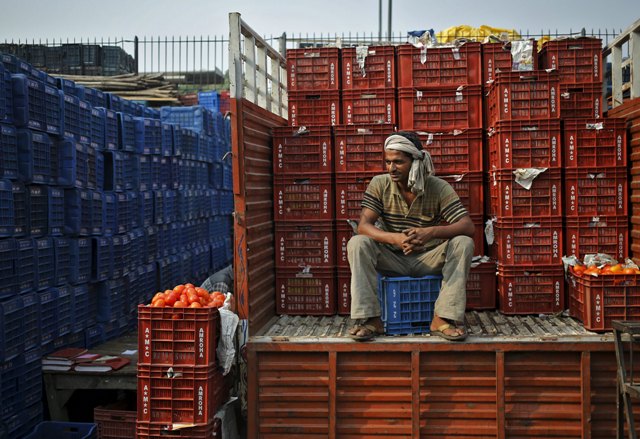 Un trabajador se sienta en un camión cargado con cestas de tomates en un mercado de verduras al por mayor en Nueva Delhi, India, 14 de octubre de 2015. Los precios al por mayor de la India cayeron durante un mes consecutivo número 11 en septiembre, cayendo un 4,54 por ciento anual, principalmente en la parte posterior de caer los precios del petróleo, los datos del gobierno mostraron el miércoles. REUTERS / Anindito Mukherjee