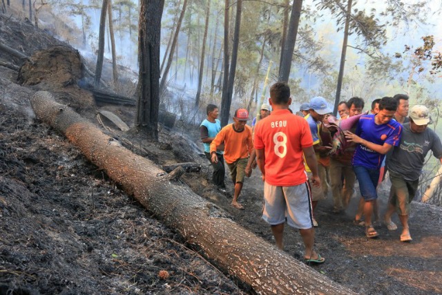 Aldeanos indonesios llevan el cadáver de una de las cuatro víctimas de un incendio forestal en Ponorogo, Java Oriental, el 29 de octubre de 2015. Cuatro personas han muerto, mientras que la extinción de un incendio que estalló en una montaña en Ponorogo, dijo un funcionario el octubre 29. civiles desesperados en el epicentro de la crisis de la neblina de Indonesia están tomando la lucha en sus propias manos, utilizando todos los recursos escasos que tienen que hacer frente a los incendios que asola sus comunidades, ya que se cansan de esperar que el gobierno a tomar medidas. AFP PHOTO