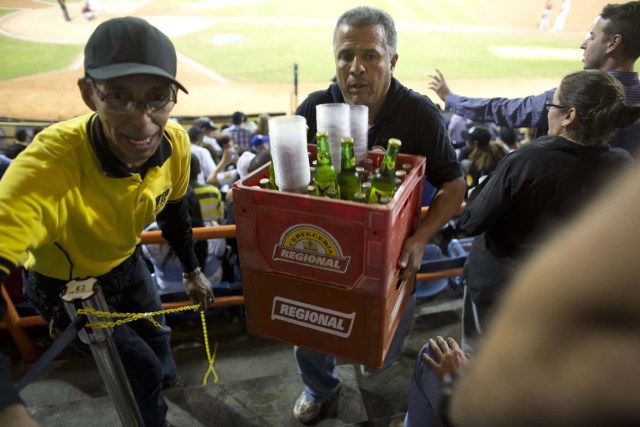 Un vendedor carga envases de cerveza durante un juego de béisbol entre los Leones de Caracas y los Navegantes de Magallanes en Caracas, Venezuela. Los aficionados no están contentos con la noticia de que el precio de la botella se incrementó de 30 a 120 bolívares en el último año, y las marcas más populares ya no están a la venta. (Foto AP/Ariana Cubillos)