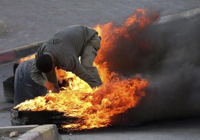 Un manifestante palestino quema unos neumáticos usados para levantar una barricada durante los enfrentamientos con las fuerzas de seguridad israelíes en Beit Ommar, en la localidad cisjordana de Hebrón (Palestina) hoy, 3 de noviembre de 2015. Por otro lado, las fuerzas israelíes clausuraron esta madrugada la emisora de radio palestina Al-Hurriya acusada de incitar a la violencia. EFE/Abed Al Hashlamoun