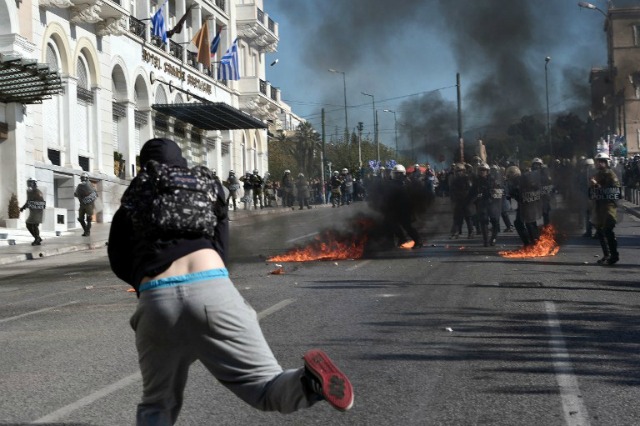 La policía griega hacen guardia en medio cócteles molotov lanzados por los manifestantes durante una manifestación masiva en el marco de una huelga general de 24 horas en Atenas el 12 de noviembre de 2015. Alrededor de 20.000 personas se manifestaron en contra de cortes frescos en Atenas, con brotes esporádicos de violencia, en el primero huelga general contra el gobierno izquierdista de Alexis Tspiras quien llegó al poder en un billete de anti-austeridad. AFP PHOTO / LOUISA GOULIAMAKI