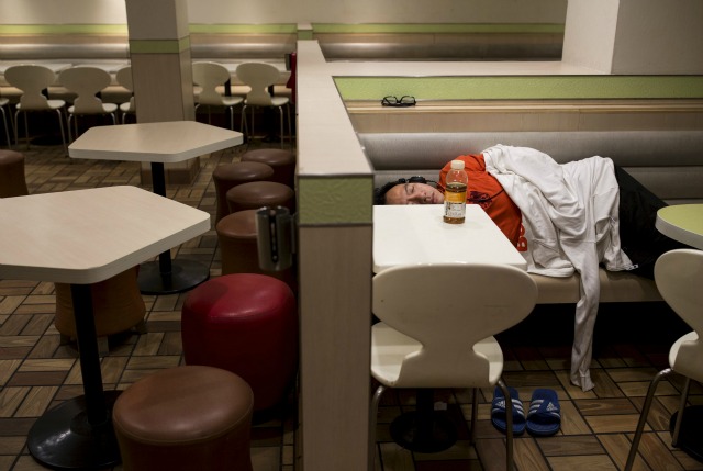 Un hombre duerme en un restaurante abierto las 24 horas McDonald en Hong Kong, China 10 de noviembre de 2015. Un gran número de personas sin hogar que duermen en la calle mucho tiempo se ha sido un problema en Hong Kong, debido principalmente a su alta renta y la propiedad en alza. En los últimos años, las 24 horas tiendas de comida rápida McDonald abren toda la ciudad se han convertido en una alternativa popular para las personas, conocido como McRefugees o McSleepers, para pasar la noche en una manera más segura y más cómoda que en la calle. Fotografía tomada el 10 de noviembre, dijo 2015. € ™ s McDonaldâ Hong Kong en un comunicado que está atento a personas que se quedan mucho tiempo en el restaurante para sus respectivas causas, mientras que lograr un buen equilibrio para asegurar que los clientes disfruten de su experiencia gastronómica. REUTERS / Tyrone Siu