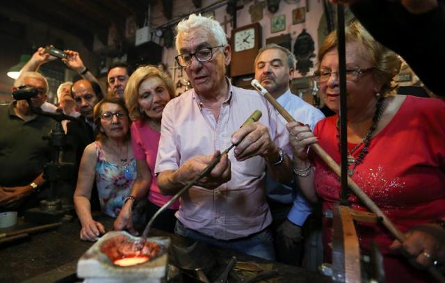 Fotografía del 16 de noviembre de 2015, del orfebre Juan Carlos Pallarols (c) mientras trabaja en su taller del centro de Buenos Aires junto a un grupo de familiares de combatientes y a excombatientes de la Guerra de Malvinas. Pallarols homenajea a los soldados caídos en la Guerra de Malvinas fundiendo fragmentos del material bélico utilizado en el fragor de la batalla para modelar dos rosas con las que espera que cada bando rinda honores al contrario. EFE/David Fernández