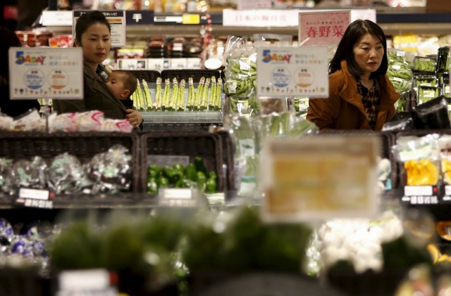 Foto de archivo de personas mirando vegetales en un supermercado en Chiba, al este de Tokio, 26 de febrero de 2014. Japón planea aumentar el salario mínimo e introducir otras medidas para revitalizar a su economía, pero el borrador del proyecto de medidas de estímulo visto el lunes por Reuters aparentemente no contempla nuevas reformas que, según analistas, son necesarias para poner fin a décadas de estancamiento. REUTERS/Yuya Shino/Files