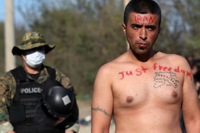 Un hombre con la boca cosida cerrada y con las leyendas 'Irán' y 'Sólo Libertad' participa en una manifestación con otros migrantes y los refugiados, ya que esperar para cruzar la greco-macedonio (también conocido como El ex Yogaslavia Rebublic de Makedonia) fronteriza cerca Idomeni el 23 de noviembre de 2015. Serbia y Macedonia, que se encuentran en la principal ruta migratoria hacia el norte de Europa, han comenzado a restringir la entrada de refugiados a poco los de ciertos países, dijo la agencia de refugiados de la ONU. AFP PHOTO / SAKIS MITROLIDIS