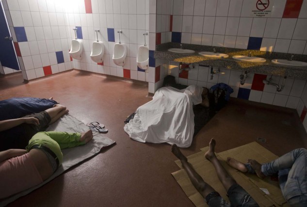 En esta foto del sábado 21 de noviembre de 2015, migrantes cubanos durmen dentro de un baño público del edificio de control fronterizo en Peñas Blancas, Costa Rica, frontera con Nicaragua. Los gobiernos centroamericanos han convocado a una reunión de emergencia sobre la reciente crisis migratoria cubana el martes en El Salvador. Nicaragua, un aliado socialista cercano a Cuba, no ha respondido públicamente a una propuesta de Costa Rica de crear un "corredor humanitario" para que los cubanos se desplacen sin obstáculos hacia Estados Unidos. (Foto AP/Esteban Félix)