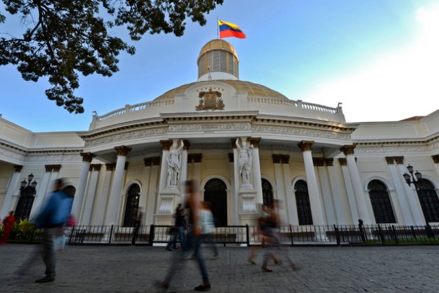 People walk past the National Assembly building in Caracas, on December 7, 2015. Venezuela's jubilant opposition vowed Monday to drag the oil-rich country out of its economic crisis and free political prisoners after winning control of congress from socialist President Nicolas Maduro. AFP  PHOTO/Luis Robayo / AFP / LUIS ROBAYO