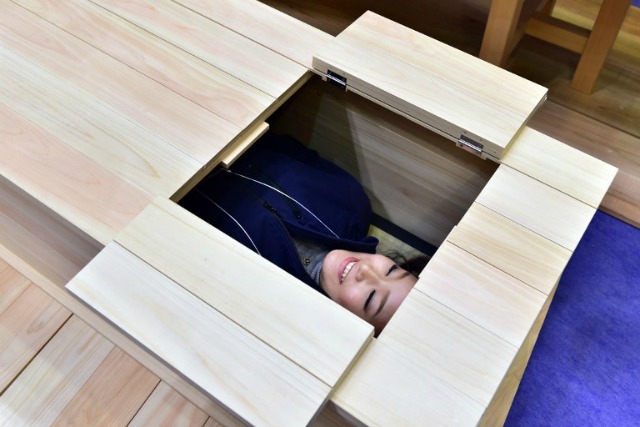 Una mujer se encuentra en un ataúd de madera en exhibición en la vida Ending Industria Expo en Tokio el 9 de diciembre de 2015. Más de 200 empresas que hacen negocios relacionados con el final de la vida, tales como funerales, están participando en la exposición de tres días. AFP PHOTO / Yoshikazu TSUNO