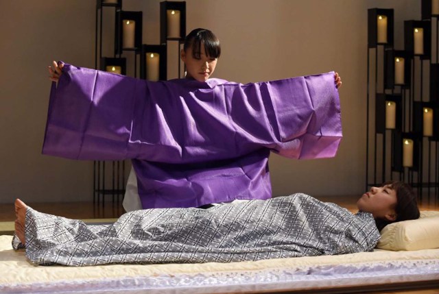 TO GO WITH AFP STORY "JAPON-SOCIETE-MORT" BY NATSUKO FUKUE AND KYOKO HASEGAWA This picture taken on December 8, 2015 shows Sayuri Takahashi (top), 27, performing her skills in "nokan" -- translated as "encoffinment", or the preparation dead bodies before cremation, during a contest at the Life Ending Industry EXPO 2015 in Tokyo.  More than 200 companies doing businesses related to the end of life, such as funerals, are participating in the three-day exhibition.  Takahashi, the competition winner who was awarded a trophy and an undisclosed sum, said she started her job three years ago after learning about the profession following a death in her own family where the body was attended to by a nokanshi, a specialist in the field.    AFP PHOTO / TOSHIFUMI KITAMURA / AFP / TOSHIFUMI KITAMURA