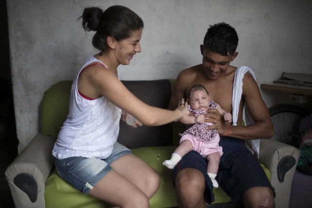 En esta imagen del 22 de diciembre de 2015, Angelica Pereira perfuma a Luiza mientras su padre Dejailson Arruda la sostiene en su casa en Santa Cruz Capibaribe, en el estado de Pernambuco, Brasil. Aunque nunca se había detectado un nexo entre el virus del zika y la microcefalia, "nunca ha habido una epidemia de zika de las proporciones que vemos ahora en Brasil", dijo Pedro Fernando Vasconcelos, investigador del instituto Evandro Chagas, que investiga una relación entre el virus y las malformaciones. (AP Foto/Felipe Dana)