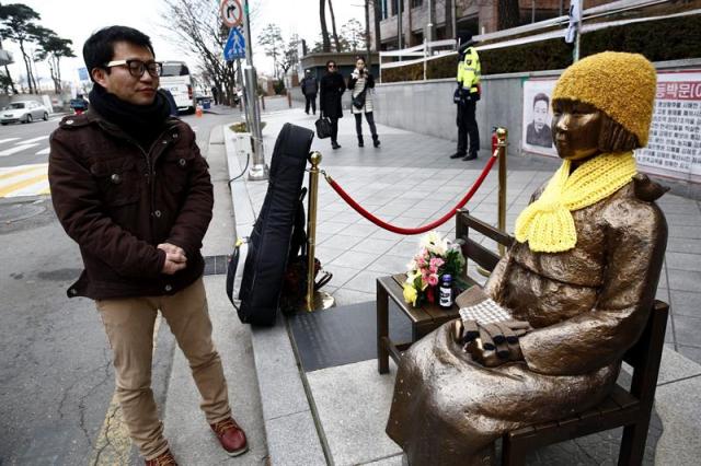 El cantante y activista surcoreano Lee Kwang-Seok (izda) observa la estatua que simboliza a las esclavas sexuales ante la embajada de Japón en Seúl (Corea del Sur) hoy, 29 de diciembre de 2015. Corea del Sur y Japón alcanzaron ayer un histórico acuerdo para zanjar la disputa de las esclavas sexuales coreanas reclutadas por el Ejército nipón en la II Guerra Mundial, un avance decisivo para reparar los lazos entre las dos democracias del nordeste de Asia. Dentro del acuerdo, Japón ha pedido la retirada de la estatua que recuerda el episodio de las esclavas sexuales ante la embajada nipona en Seúl. EFE/Jeon Heon-Kyun