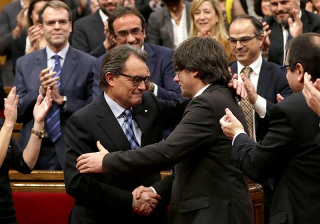 El expresidente de la Generalitat en funciones, Artur Mas (i), felicita a su sucesor, Carles Puigdemont (d), tras ser elegido nuevo presidete catalán durante el pleno de investidura celebrado en el Parlament de cataluña. EFE/Alberto Estévez