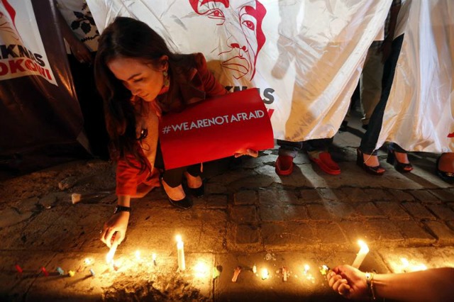 Una mujer sostiene una pancarta en la que se puede leer "no tenemos miedo" mientras enciende una vela en el lugar donde se produjo el atentado de ayer durante una manifestación en repulsa al ataque en Yakarta (Indonesia) hoy, 15 de enero de 2016. La Policía indonesia arrestó hoy a tres personas por supuestos vínculos con el ataque con explosivos y disparos, cuya autoría reclamó el Estados Islámico, ocurrido este jueves en un barrio céntrico de Yakarta, informan medios locales. Al menos siete personas, dos civiles y cinco asaltantes, perdieron la vida en el atentado, que también causó más de una veintena de heridos. EFE/Bagus Indahono