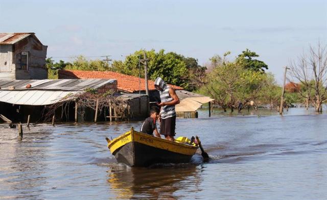 Pobladores se trasladan en canoa por una zona inundada hoy, jueves 28 de enero de 2016, en el barrio Sajonia de Asunción (Paraguay). Los evacuados por las inundaciones en Asunción, que suman unas 100.000 personas, se debaten entre volver a sus casas o permanecer en los refugios, como recomienda el Gobierno, que prevé nuevas subidas del río Paraguay. EFE/Andrés Cristaldo Benítez