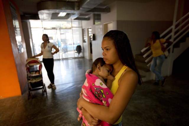 En esta foto del 11 de febrero de 2016, una mujer sostiene a su bebé enfermo mientras espera para ser atendida por un médico en una clínica, en el barrio Petare de Caracas, Venezuela. Ante la crisis del sistema de salud y la profunda escasez de medicamentos que agobia Venezuela, lo último que cualquier venezolano quiere es enfermarse. Y menos del virus del zika. Actualmente, no se consigue repelente para insectos, ni anticonceptivos para evitar embarazos, ni medicamentos para tratar las enfermedades asociadas al virus. (Foto AP / Fernando Llano)