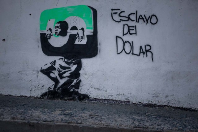 CAR01. CARACAS (VENEZUELA), 09/03/2016.- Vista de un grafiti con la frase "Esclavo del Dolar" hoy, miércoles 9 de marzo de 2016, en la ciudad de Caracas (Venezuela). El vicepresidente de Economía Productiva de Venezuela, Miguel Pérez Abad, anunció hoy que la tasa de cambio en divisas para los venezolanos que deseen viajar al exterior será más de un 1.500 por ciento superior a la que se aplicaba hasta ahora, de acuerdo a los ajustes del nuevo sistema cambiario. EFE/MIGUEL GUTIERREZ