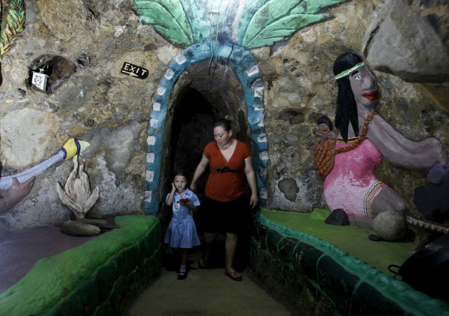 Lidieth Barrantes y su hija a pie en un pasillo de una casa construida bajo tierra por Manuel Barrantes en San Isidro de Pérez Zeledón, Costa Rica, 14 de marzo de 2016. Barrantes empezó a cavar a través del suelo rojo y roca volcánica en su granja hace 12 años para construir su casa subterránea, entre 15 y 63 pies (4,57 y 19,2 M) bajo tierra. La vivienda, que dice Barrantes ofrece un hogar tranquilo y cómodo para él y su familia lejos de la contaminación acústica y los efectos del cambio climático, ahora cubre alrededor de 2.000 pies cuadrados (185,8 metros cuadrados). Fotografía tomada 14 de marzo de 2016. REUTERS / Juan Carlos Ulate TPX IMÁGENES DEL DÍA