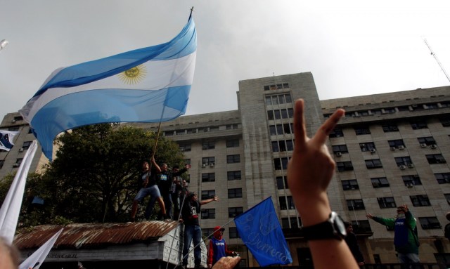 Supporters of former Argentine President Cristina Fernandez de Kirchner wave an Argentine national flag outside a Justice building where she attended court to answer questions over a probe into the sale of U.S. dollar futures contracts at below-market rates by the central bank during her administration, in Buenos Aires, Argentina, April 13, 2016. REUTERS/Martin Acosta