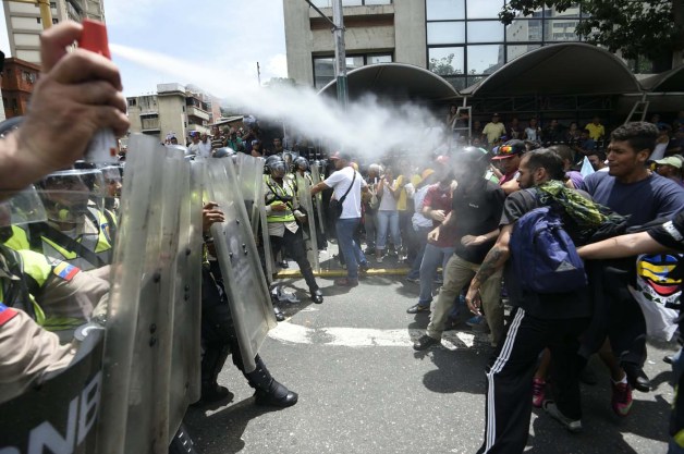 People clash with police as they protest against new emergency powers decreed this week by President Nicolas Maduro in Caracas on May 18, 2016. Public outrage was expected to spill onto the streets of Venezuela Wednesday, with planned nationwide protests marking a new low point in Maduro's unpopular rule. / AFP PHOTO / JUAN BARRETO