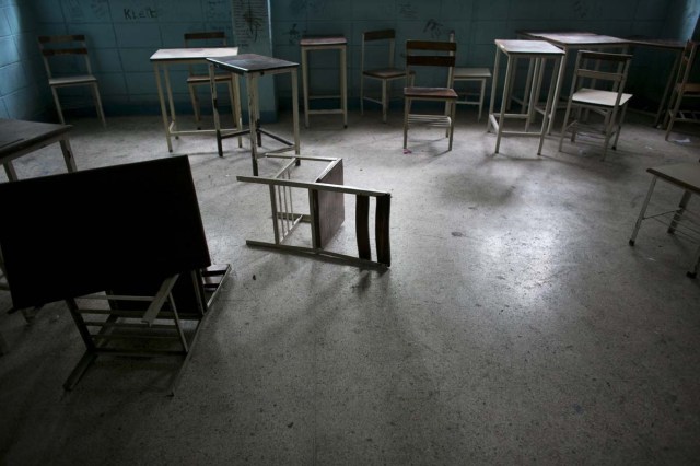 Fotografía del 1 de junio de 2016 muestra sillas y escritorios en un salón de clases abandonado en una escuela secundaria pública en Caracas, Venezuela. Oficialmente, Venezuela canceló este año 16 días de escuela, incluyendo clases del viernes, debido a una crisis de producción de electricidad. En realidad, los niños venezolanos están perdiendo ahora un promedio de 40% de tiempo de clases, calculó un grupo de padres de familia, y una tercera parte de los maestros falta a clases cualquier día dado para formarse en filas para conseguir alimento. (AP Foto/Ariana Cubillos)