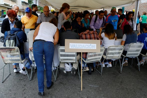 People stand in line as they gather outside a validation center during Venezuela’s National Electoral Council (CNE) second phase of verifying signatures for a recall referendum against President Nicolas Maduro in Caracas, Venezuela, June 20, 2016. The placard reads "Validation". REUTERS/Ivan Alvarado