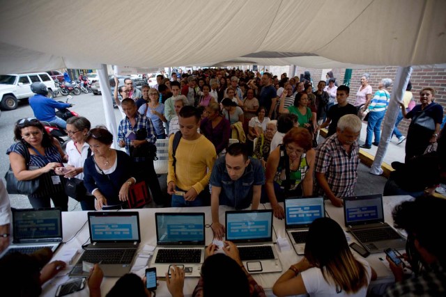 La gente hace fila para certificar sus firmas en la sede del Consejo Nacional Electoral de Venezuela, CNE, en Caracas, Venezuela, el lunes 20 de junio de 2016. Para activar una nueva etapa del proceso del referendo revocatorio del mandato del presidente Nicolás Maduro, la oposición debe lograr la validación de al menos 196.000 firmas. De superarse esta etapa la oposición deberá emprender la recolección de más de cuatro millones de firmas para lograr activar formalmente la consulta popular. (Foto AP / Fernando Llano)