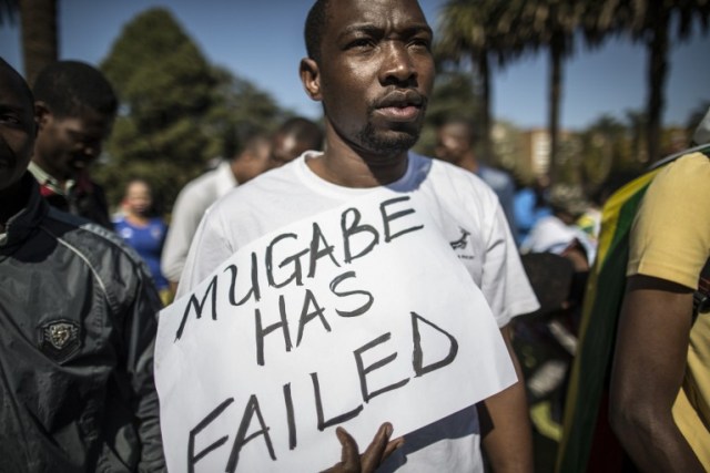 A Zimbabwean "myflag" activist holds a placad in Pretoria on July 14, 2016 during a march to the Zimbabwe embassy. / AFP PHOTO / MARCO LONGARI