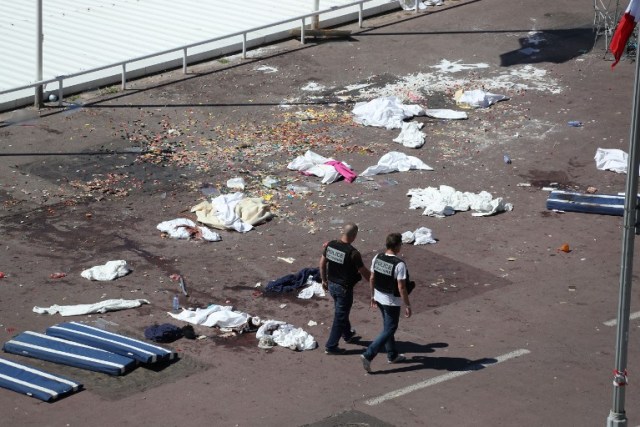 Policemen walk on the site where a truck drove into a crowd watching a fireworks display on the Promenade des Anglais seafront in the French Riviera town of Nice on July 15, 2016. An attack in Nice where a man rammed a truck into a crowd of people left 84 dead and another 18 in a "critical condition", interior ministry spokesman Pierre-Henry Brandet said Friday. An unidentified gunman barrelled the truck two kilometres (1.3 miles) through a crowd that had been enjoying a fireworks display for France's national day before being shot dead by police. / AFP PHOTO / Valery HACHE