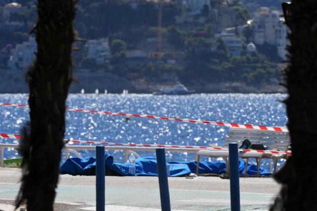 Dead bodies covered with blue sheets are pictured on the Promenade des Anglais seafront in the French Riviera city of Nice on July 15, 2016, a day after a gunman smashed a truck into a crowd of revellers celebrating Bastille Day, killing at least 84 people. Authorities said they found identity papers belonging to a 31-year-old French-Tunisian citizen in the 19-tonne truck, and that the driver had fired a gun several times before police shot him dead. / AFP PHOTO / BORIS HORVAT