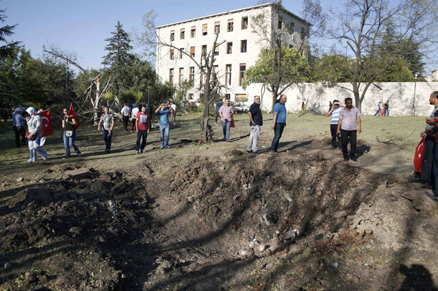 People stand around a crater outside the parliament building in Ankara, Turkey, July 16, 2016. REUTERS/Baz Ratner