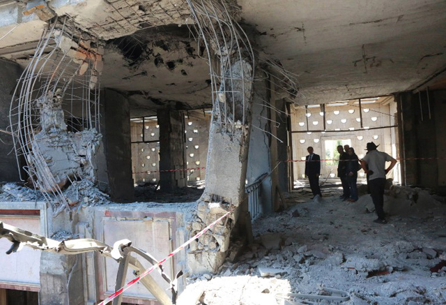 People inspect damage after the Grand National Assembly of Turkey was bombed by rebel jets, on July 16, 2016 in Ankara. July 15 putsch bid began with rebel F-16 jets screaming low over rooftops in Ankara, soldiers and tanks taking to the streets and multiple explosions throughout the night in the capital as well as the biggest city Istanbul. With at least 2,839 soldiers already detained in a relentless round-up over the coup plot, the authorities blamed the conspiracy on Erdogan's arch enemy, the US-based cleric Fethullah Gulen. / AFP PHOTO / ADEM ALTAN