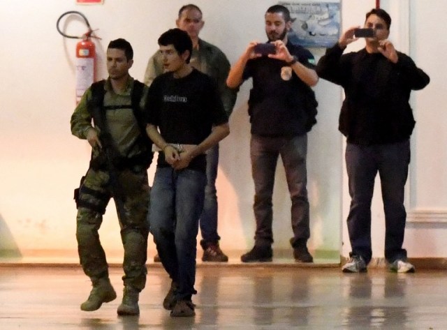 Un presunto terrorista anda escoltado por la policía en el hangar de la Policía Federal de Brasil en el aeropuerto de Brasilia el 21 de julio de 2016. La policía brasileña ha detenido a 10 miembros de un "aficionado" a los posibles grupo terrorista que expresa lealtad a la organización Estado Islámico y estaba dirigido a los próximos Juegos Olímpicos, según las autoridades. AFP PHOTO / EVARISTO SA