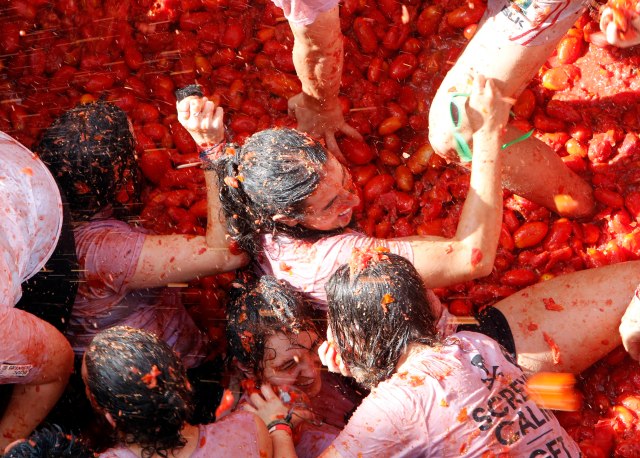 Un grupo de personas se lanza tomates durante la fiesta anual dedicada a este producto, conocida como"Tomatina", en la localidad de Buñol, a 50 kms de Valencia, en España, el 31 de agosto de 2016. Las calles de la localidad levantina se tiñen de rojo con la pulpa del tomate mientras miles de personas se lanzan frutas maduras. Camiones vertieron 160 toneladas de tomates que hicieron las delicias de unos 20.000 participantes, la mayoría extranjeros. (AP Foto/Alberto Saiz)